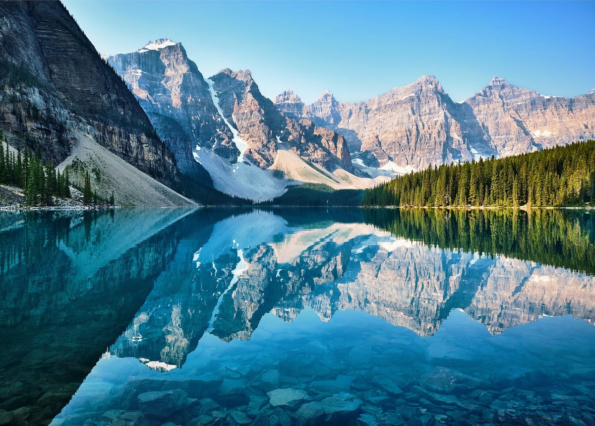 Turquoise alpine lake reflecting snow-dusted peaks in the Canadian Rockies, Alberta.