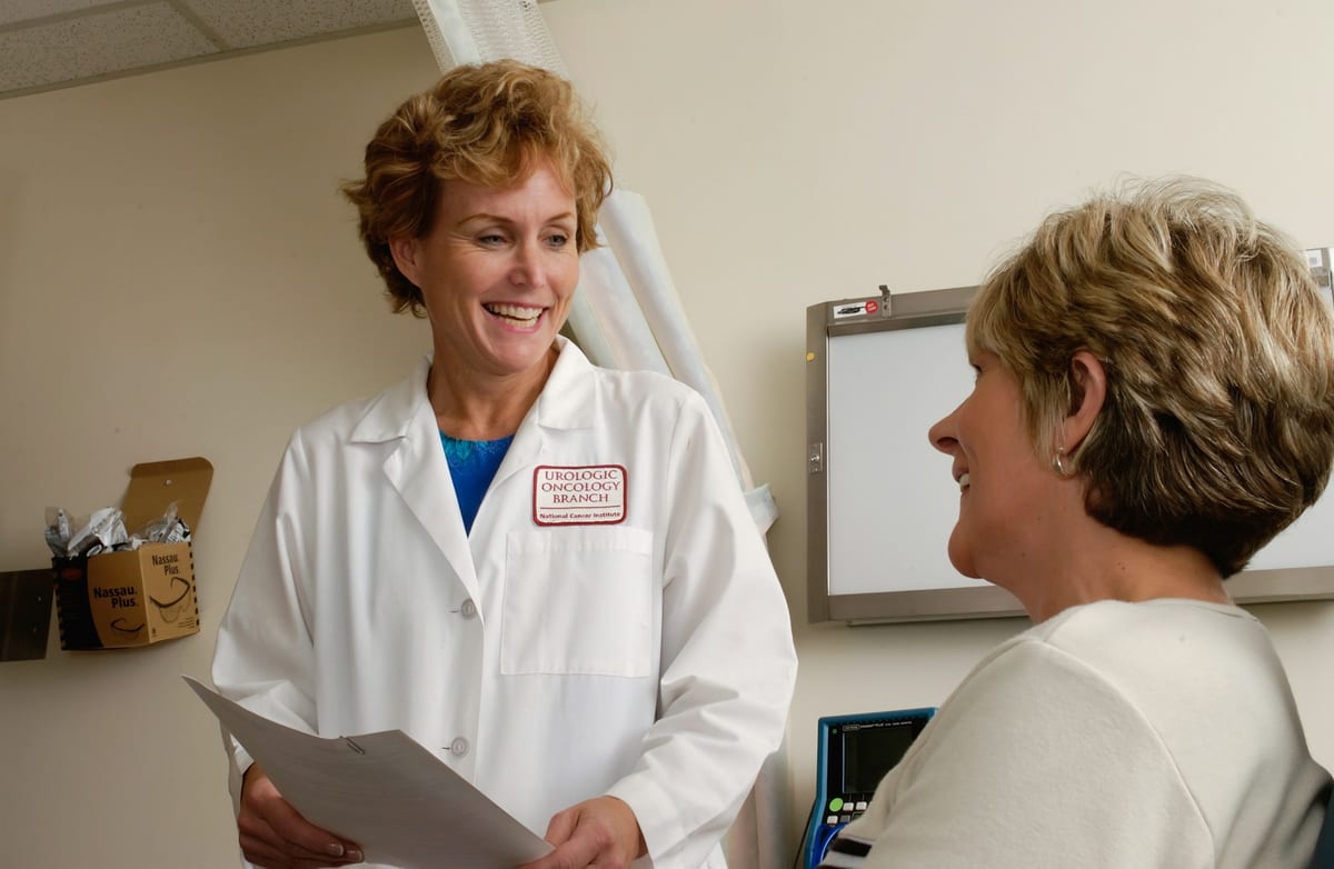 A clinician speaking warmly with an older patient during a calm consultation.