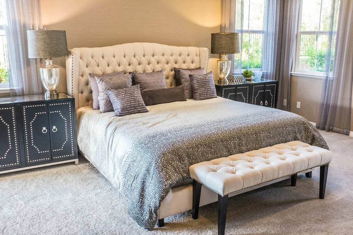 A calm, well-lit bedroom with soft neutrals and inviting bedding.