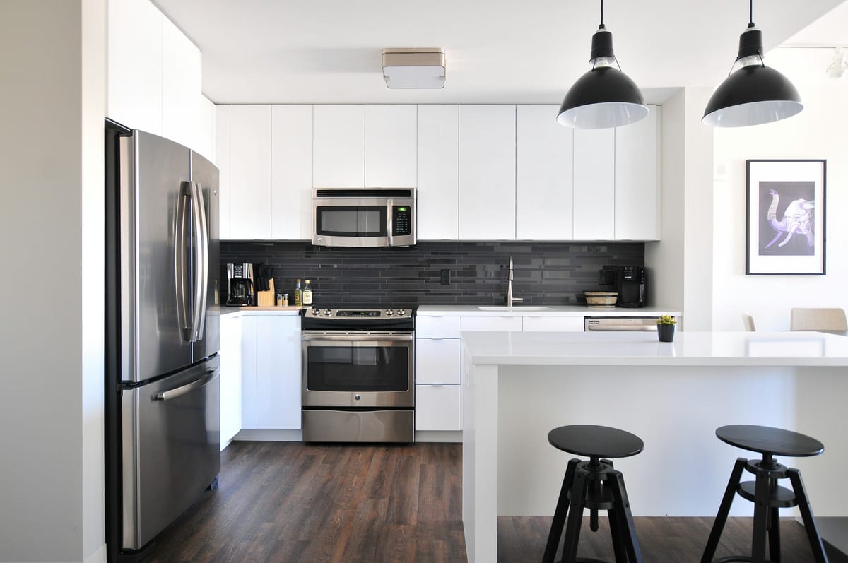A bright, modern residential kitchen with warm wood floors and natural light.